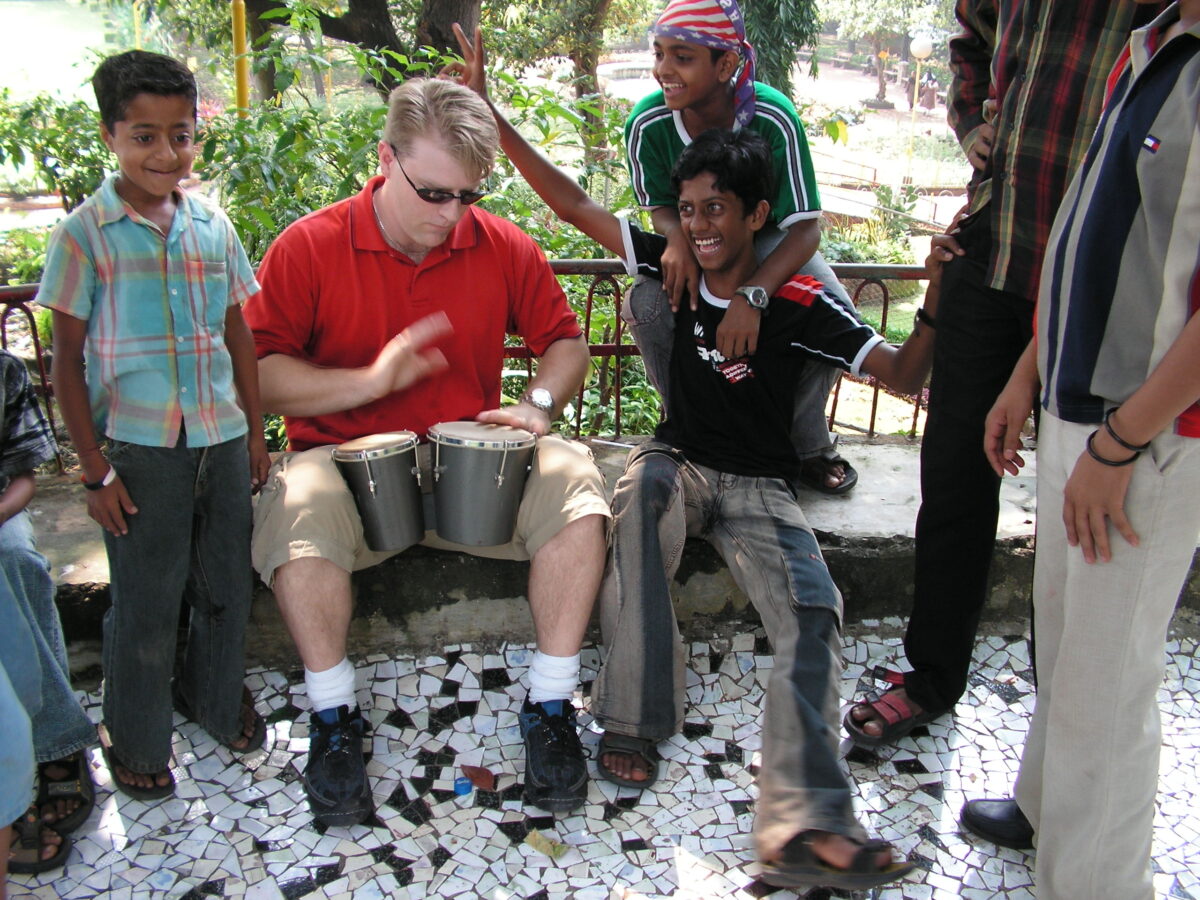 Travel author Steve Page plays bongos drums in a park with the local kids in India