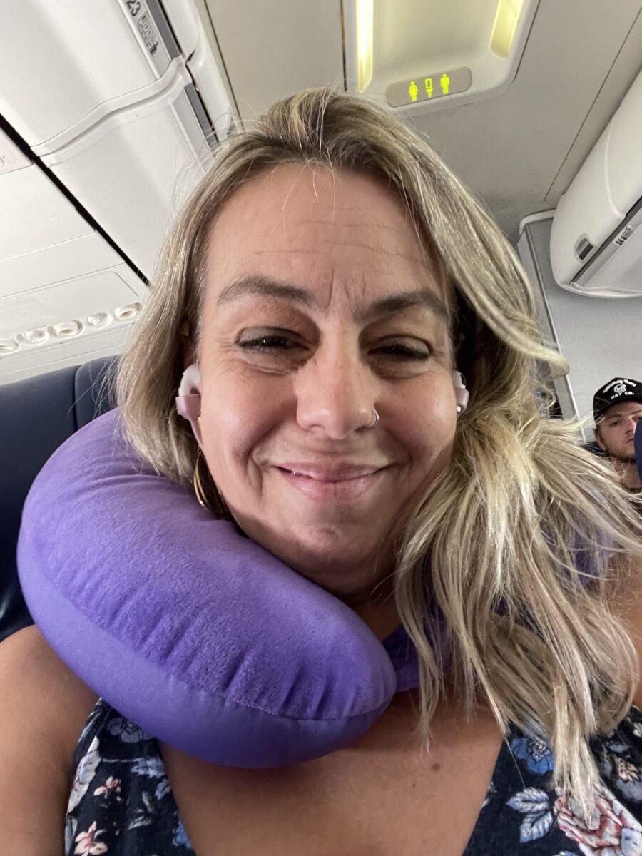 Travel author Nikki Page on Southwest flight with purple travel pillow 