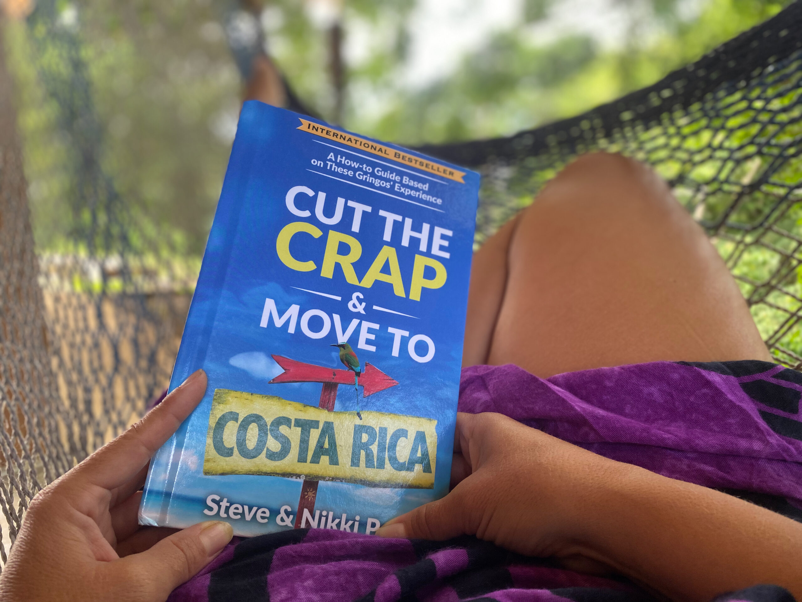 Cut the Crap & Move to Costa Rica Hardcover book being held in a hammock
